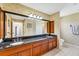 Bathroom with double sinks, granite counters, wood cabinets, and seashell themed wallpaper at 1714 Coral Sands Ct, Venice, FL 34293