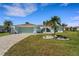 Charming single-story home with a well-manicured lawn, palm trees, and a paved driveway leading to a two-car garage at 1714 Coral Sands Ct, Venice, FL 34293