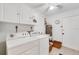 Bright laundry room with white washer and dryer, storage cabinets, and tiled floor at 1714 Coral Sands Ct, Venice, FL 34293
