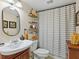 Neutral bathroom features updated fixtures, decorative shelving, and a tub with a striped shower curtain at 2526 Clubhouse Dr # 203, Sarasota, FL 34232