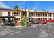Beige condo building with carport and well-maintained landscaping, and multiple cars parked in the lot at 2526 Clubhouse Dr # 203, Sarasota, FL 34232