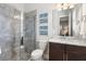 A bathroom with a glass shower door and a brown vanity with marble countertop at 4790 Pastel Ct, Sarasota, FL 34240