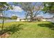 Large, green backyard with a screen-enclosed pool area, a mature shade tree, and a white fence creating a private outdoor oasis at 4920 Breakwater Dr, Bradenton, FL 34203