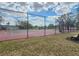 Well-maintained community tennis court with a red and gray surface, surrounded by a chain-link fence and mature trees at 4920 Breakwater Dr, Bradenton, FL 34203