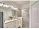 Bright main bathroom featuring double vanity sinks, tile flooring, a glass-enclosed shower and a linen closet at 5433 Mystic Water Cv, Lakewood Ranch, FL 34211