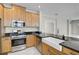 Kitchen with stainless steel appliances, granite countertops, a farmhouse sink, and natural wooden cabinets at 5675 Equator Ct, Nokomis, FL 34275