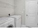 Functional laundry room with modern washer, dryer, and overhead shelving for organized storage solutions at 5675 Equator Ct, Nokomis, FL 34275