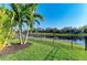 Lush backyard featuring a black metal fence, palm trees, and serene water views for a tranquil outdoor setting at 5709 Sunflower Cir, Sarasota, FL 34238