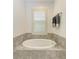 Soaking tub with tile surround and a window with plantation shutters, creating a spa-like atmosphere at 5709 Sunflower Cir, Sarasota, FL 34238