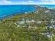 Expansive aerial shot showcasing waterfront property surrounded by lush greenery, and nearby beach access at 691 & 681 Gulf Bay Rd, Longboat Key, FL 34228