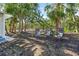 Backyard seating area with three cushioned chairs in a partially shaded grassy backyard at 691 & 681 Gulf Bay Rd, Longboat Key, FL 34228