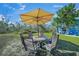 Outdoor dining table with six chairs under a large umbrella in a beautifully manicured backyard at 691 Gulf Bay Rd, Longboat Key, FL 34228