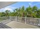 Outdoor deck with a white railing offers views of lush palm trees and clear blue skies at 691 Gulf Bay Rd, Longboat Key, FL 34228