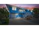 Charming two-story home with a garage, a front porch, and stairs, beautifully lit at dusk at 691 Gulf Bay Rd, Longboat Key, FL 34228