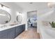Bright bathroom featuring double sinks, dark blue cabinets, tiled shower and view to main bedroom at 7717 Mainsail Ln, Sarasota, FL 34240