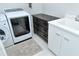 Laundry room includes modern appliances and white and black cabinets with a white tile floor at 7744 Sandhill Lake Dr, Sarasota, FL 34241