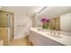 Bright bathroom featuring double vanity, large mirror, and glass-enclosed shower with decorative tile accents at 800 N Tamiami Trl # 1506, Sarasota, FL 34236