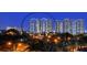 A night view of a high-rise building with balconies and windows, surrounded by trees and lights at dusk at 800 N Tamiami Trl # 1506, Sarasota, FL 34236