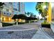 Well-lit walkway with brick pavers, lush landscaping, and swaying palm trees creates an inviting path to the building entrance at 800 N Tamiami Trl # 1506, Sarasota, FL 34236