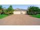Exterior view of home showing three-car garage, beautiful landscaping, and brick-paved driveway at 8007 River Preserve Dr, Bradenton, FL 34212
