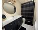 Nicely decorated bathroom with round mirror, black vanity, and patterned shower curtain at 810 Hammockwood Ct, Sarasota, FL 34232