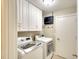 Functional laundry room equipped with modern washer and dryer, ample cabinet space, and a tankless water heater at 8111 Timber Lake Ln, Sarasota, FL 34243