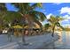 Outdoor dining and a Tiki hut bar with yellow umbrellas on a white sandy beach and blue sky at 850 S Tamiami Trl # 307, Sarasota, FL 34236