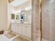 Bathroom featuring double vanity with framed mirror, tiled shower with glass doors, and neutral flooring at 9441 Discovery Ter # 101A, Bradenton, FL 34212