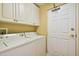 Functional laundry room with side by side washer and dryer, cabinets and a door at 9441 Discovery Ter # 101A, Bradenton, FL 34212