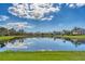 Scenic view of a pond with neighborhood homes reflecting against a bright blue sky with fluffy white clouds at 9612 Old Hyde Park Pl, Bradenton, FL 34202