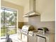 Close up of the built-in outdoor kitchen with stainless steel grill, pizza oven, refrigerator, and tiled backsplash at 11511 Harbourside Ln, Parrish, FL 34219