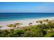 Expansive view of a serene beach with white sand, clear water, and tropical vegetation under a blue sky at 1211 Gulf Of Mexico Dr # 702, Longboat Key, FL 34228