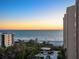 Panoramic ocean view from the property, showcasing the beach, trees, and sunset with other buildings at 1211 Gulf Of Mexico Dr # 702, Longboat Key, FL 34228