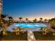 Stunning waterfront pool with lounge chairs surrounded by palm trees with a beautiful sunset at 1211 Gulf Of Mexico Dr # 702, Longboat Key, FL 34228