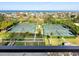 Aerial view showcasing well-maintained tennis courts surrounded by manicured landscaping, near the ocean at 1211 Gulf Of Mexico Dr # 702, Longboat Key, FL 34228
