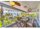 Inviting screened-in porch with a dining table, ceiling fans, and scenic views of the surrounding tropical landscape at 123 Hammock Rd, Anna Maria, FL 34216