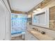 Rustic bathroom featuring wood paneling, granite countertops, and a charming tropical-themed shower curtain at 123 Hammock Rd, Anna Maria, FL 34216