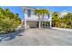 Inviting stilt home featuring a well-maintained gravel driveway and lush tropical landscaping at 123 Hammock Rd, Anna Maria, FL 34216