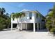 Charming stilt home with a pristine white exterior, lush landscaping, and ample parking at 123 Hammock Rd, Anna Maria, FL 34216