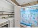 Bright laundry room with modern washer and dryer, shelving, and adjacent bathroom with beach-themed shower curtain at 123 Hammock Rd, Anna Maria, FL 34216
