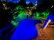 Tranquil backyard with private pool and lush, illuminated landscaping for serene evenings at 123 Hammock Rd, Anna Maria, FL 34216