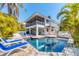 Inviting pool area with sun loungers, surrounded by lush tropical landscaping and white picket fence at 123 Hammock Rd, Anna Maria, FL 34216