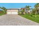 Beautiful home with a brick driveway, a 2-car garage, and a well-manicured lawn with palm trees at 16211 Cayman Ln, Punta Gorda, FL 33955