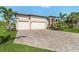A beautiful home featuring a brick driveway, a 2-car garage, and a well-manicured lawn with palm trees at 16211 Cayman Ln, Punta Gorda, FL 33955