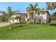 Beautifully landscaped home featuring lush green grass and tropical palm trees at 16211 Cayman Ln, Punta Gorda, FL 33955