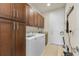 A spacious laundry room features wooden cabinetry, a granite sink, and a modern washer and dryer set at 16211 Cayman Ln, Punta Gorda, FL 33955