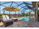 Relaxing screened pool with lounge chairs and umbrella, perfect for enjoying the Florida sunshine at 16211 Cayman Ln, Punta Gorda, FL 33955