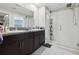 Bright bathroom showcasing a glass shower, granite countertops, and dark wood cabinets at 16621 Sunburst Lake St, Wimauma, FL 33598