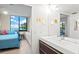 Bright bathroom featuring modern sink with wood trim and lighting, adjacent to bedroom with ocean view at 1945 Gulf Of Mexico Dr # M2-110, Longboat Key, FL 34228