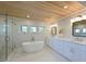 Bright bathroom with a soaking tub, glass-enclosed shower, double vanity, and wood plank ceiling at 206 23Rd W St, Bradenton, FL 34205